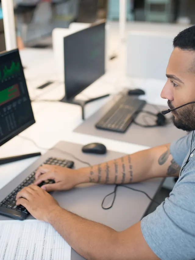Man examining data on computer monitors; illustrative photo, not a Razer latency measurement