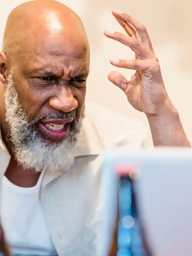 Concerned man looking at a laptop while raising his hand