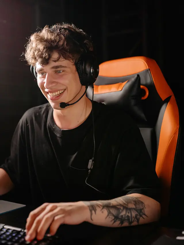 A gamer smiling at his computer with a hand on a mouse; illustrative stock, not a SteelSeries product test