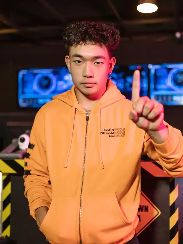 The recurring orange-hoodie gamer raising one finger in a gaming venue; stock illustration of a buying caveat, not a product endorsement