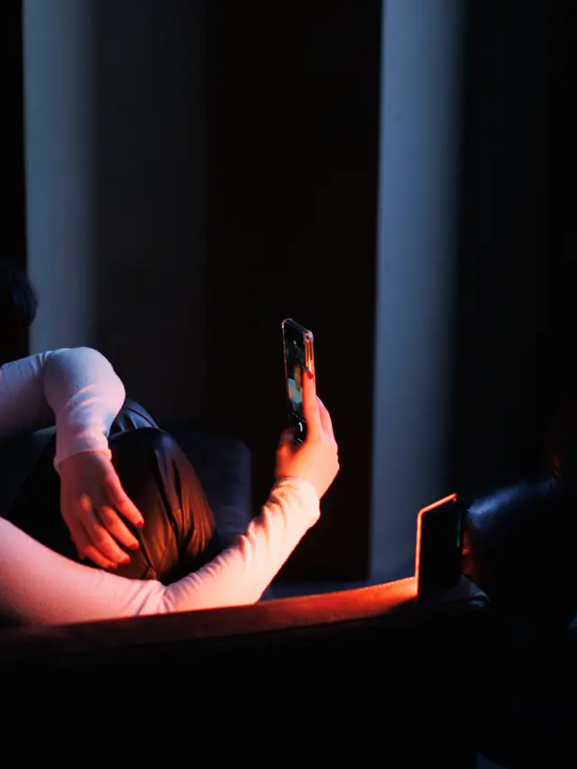 Woman calmly using her smartphone in a dimly lit room