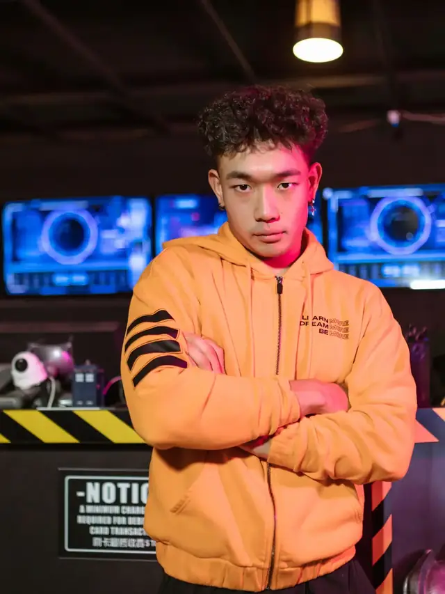 The same orange-hoodie man standing thoughtfully in a gaming venue; stock illustration of deciding to keep existing hardware