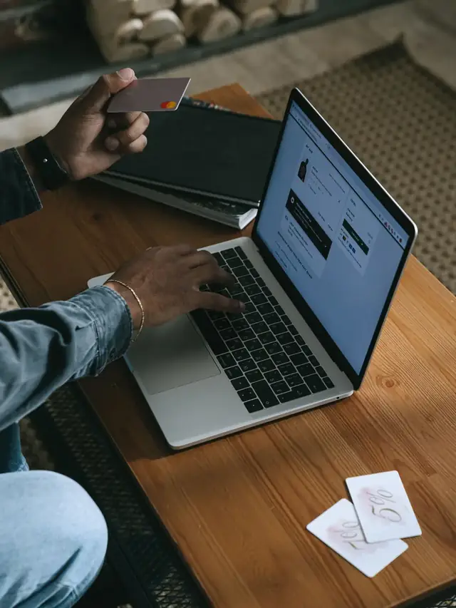 A person comparing options on a laptop with a card nearby; stock illustration of a parts budget