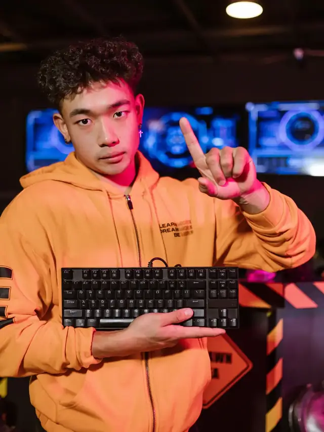 The same orange-hoodie man holding a generic keyboard and raising a finger; stock illustration of a compatibility check