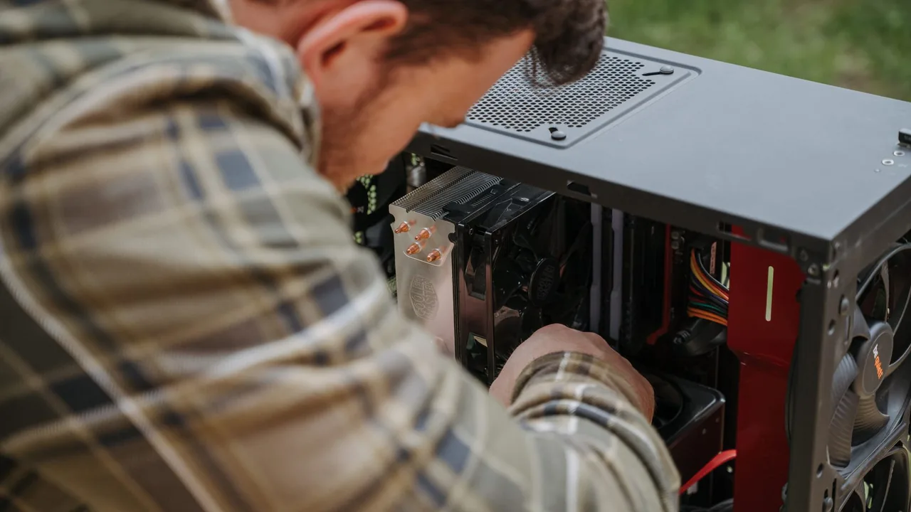 Person working inside an open desktop PC tower to check the CPU cooler and graphics card before a bottleneck check